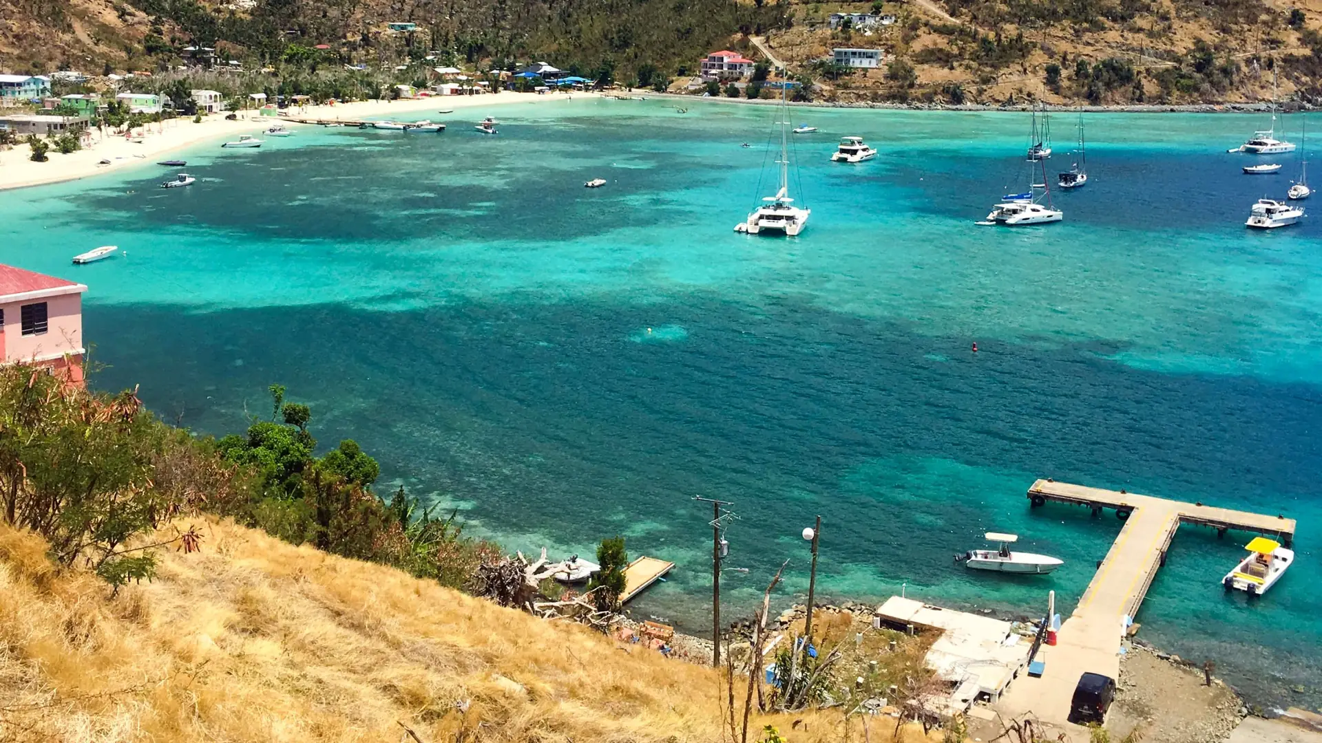 Great Harbour, Jost Van Dyke, seen from the hillside: a quiet ferry and customs dock in the foreground and yachts anchored in a calm turquoise bay