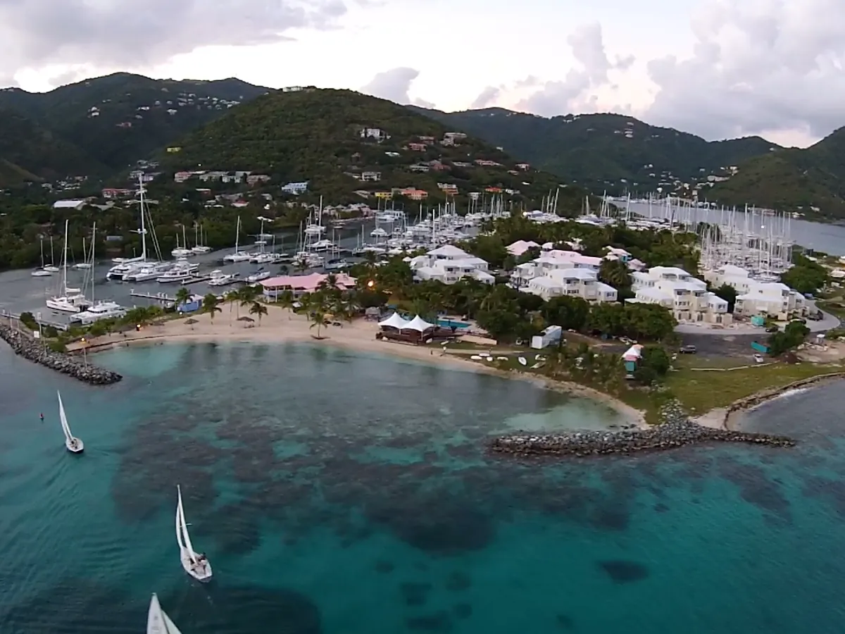 Aerial view of Nanny Cay marina and beach on Tortola, with sailboats at anchor in the bay and green hills behind